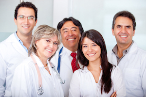 Four Medical Professionals smiling. There is two females and three males.
